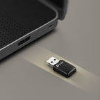 TP-Link USB WiFi adapter positioned near laptop USB port on a grey surface