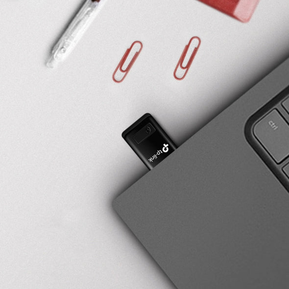 TP-Link USB WiFi adapter plugged into laptop with pen and red paperclips on desk
